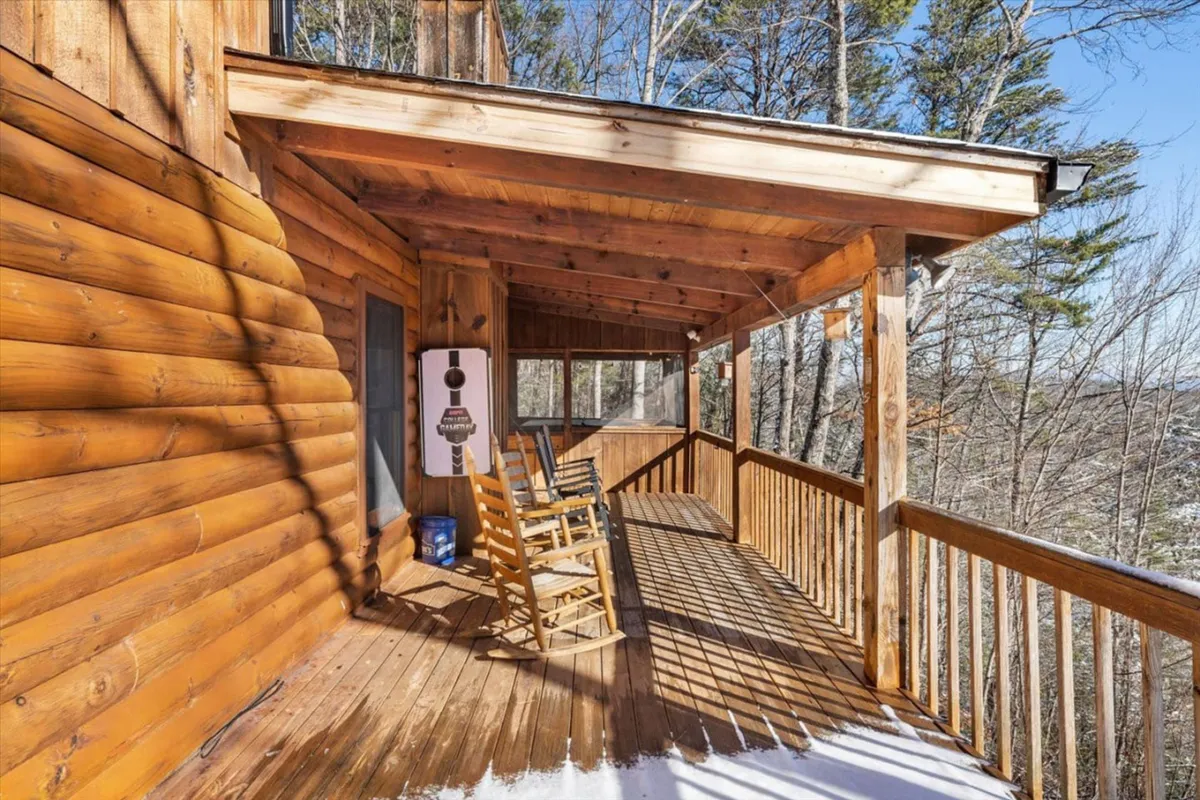 This image showcases a set of wooden rocking chairs lined up along a porch with a sturdy wooden railing, backed by a lush natural landscape. The tranquil mood is enhanced by the soft light, inviting guests to relax and soak in the scenery—perfect for evening conversations or morning gatherings.